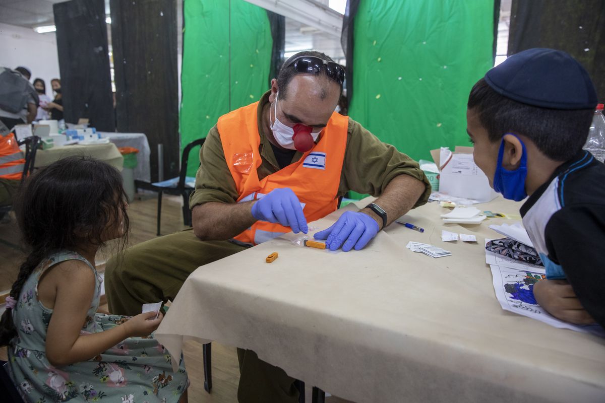 An Israeli soldier conducts a COVID-19 antibody test on a child in Hadera, Israel, Monday, Aug. 23, 2021. Ahead of the opening of the school year on Sept. 1, the Israeli army