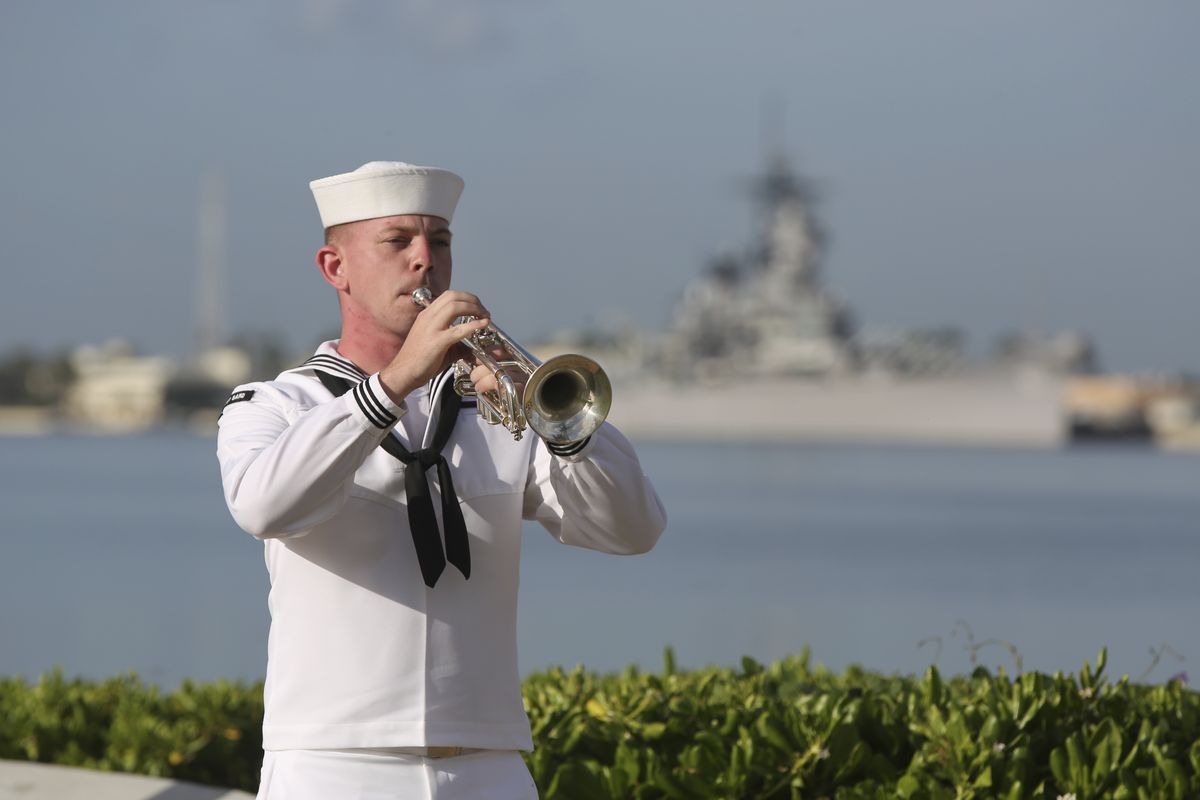 A U.S. Navy sailor plays taps Monday in front of the USS Missouri during a ceremony to mark the anniversary of the attack on Pearl Harbor in Pearl Harbor, Hawaii. Officials gathered in Pearl Harbor to remember those killed in the 1941 Japanese attack, but public health measures adopted because of the coronavirus pandemic meant no survivors were present.  (Caleb Jones)