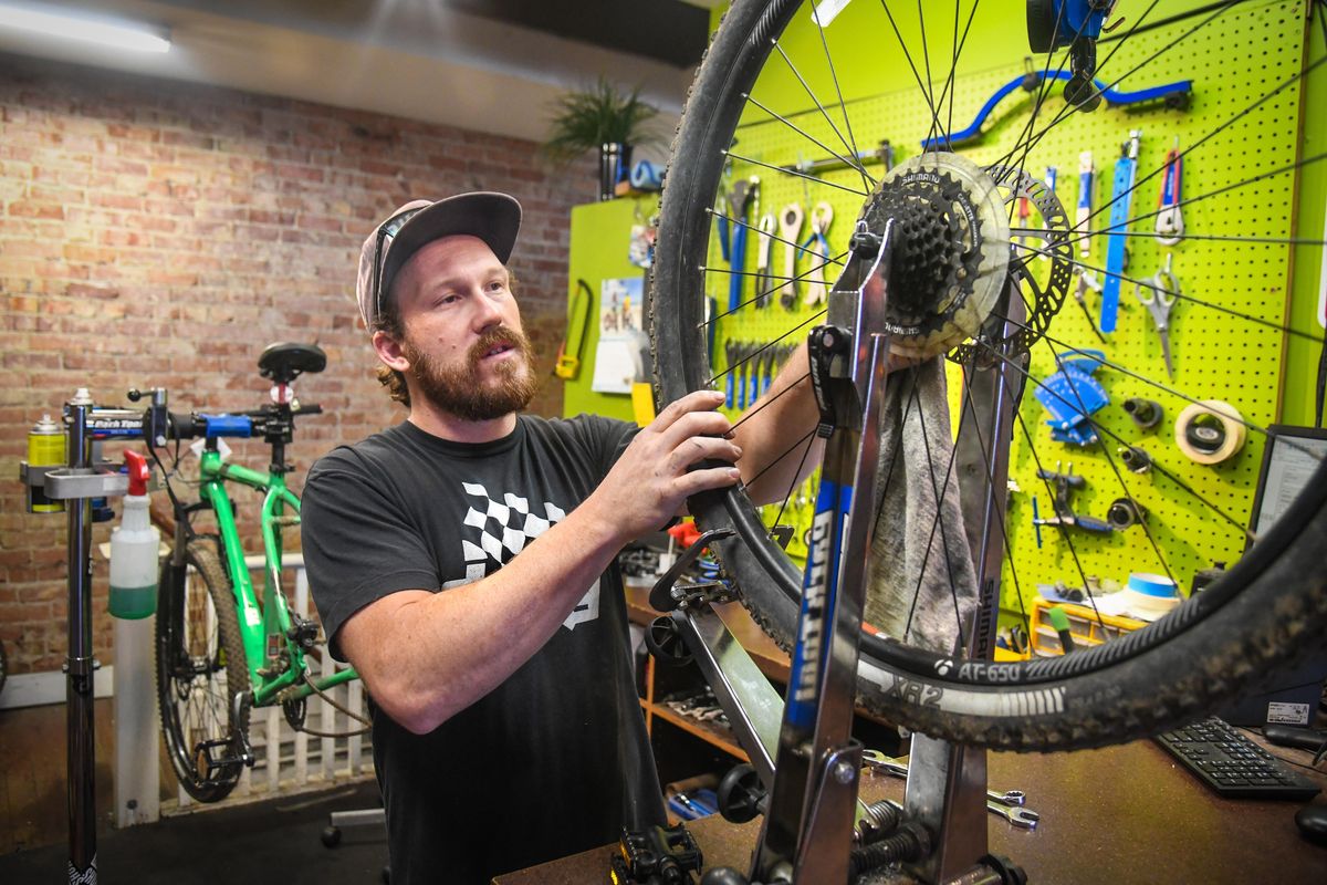Bike Hub head mechanic Justin Covey cleans a mountain bike rim and tire on a truing stand, Thursday, May 21, 2020, in downtown Spokane. He said he has been repairing and tuning up to eight  bikes a day during the pandemic. (Dan Pelle / The Spokesman-Review)