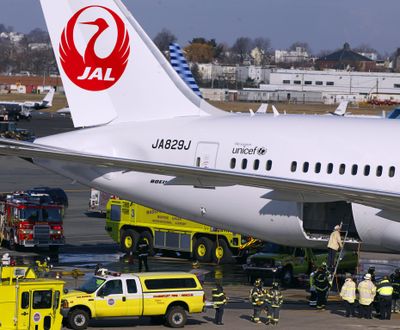 In this Jan. 7 file photo, a Japan Airlines Boeing 787 aircraft is surrounded by emergency vehicles while parked at a terminal E gate at Logan International Airport in Boston as a fire chief looks into the cargo hold. (Associated Press)