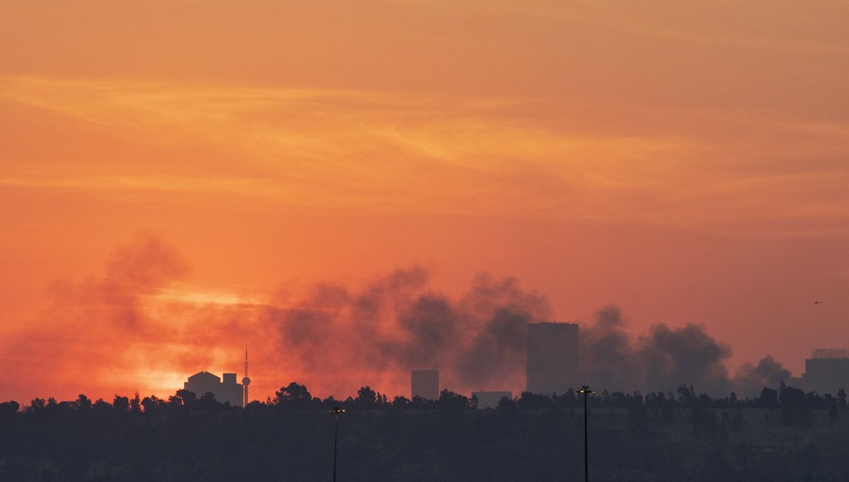 Smoke covers the Johannesburg skyline as people protests in downtown area, in Johannesburg, South Africa, Sunday, July 11, 2021. Protests have spread from the KwaZulu Natal province to Johannesburg against the imprisonment of former South African President Jacob Zuma who was imprisoned last week for contempt of court.  (Themba Hadebe)
