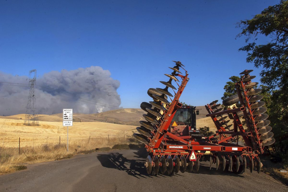 In this Tuesday, July 17, 2018, photo, a tractor with a disk trailer rolls toward the Substation Fire on its’ way to cut fire lines just of Highway 197 south of The Dalles, Ore. Gov. Kate Brown has invoked an emergency order in response to a wildfire burning in two north-central Oregon counties with mandatory evacuations for dozens of households. (Mark Gibson / Associated Press)