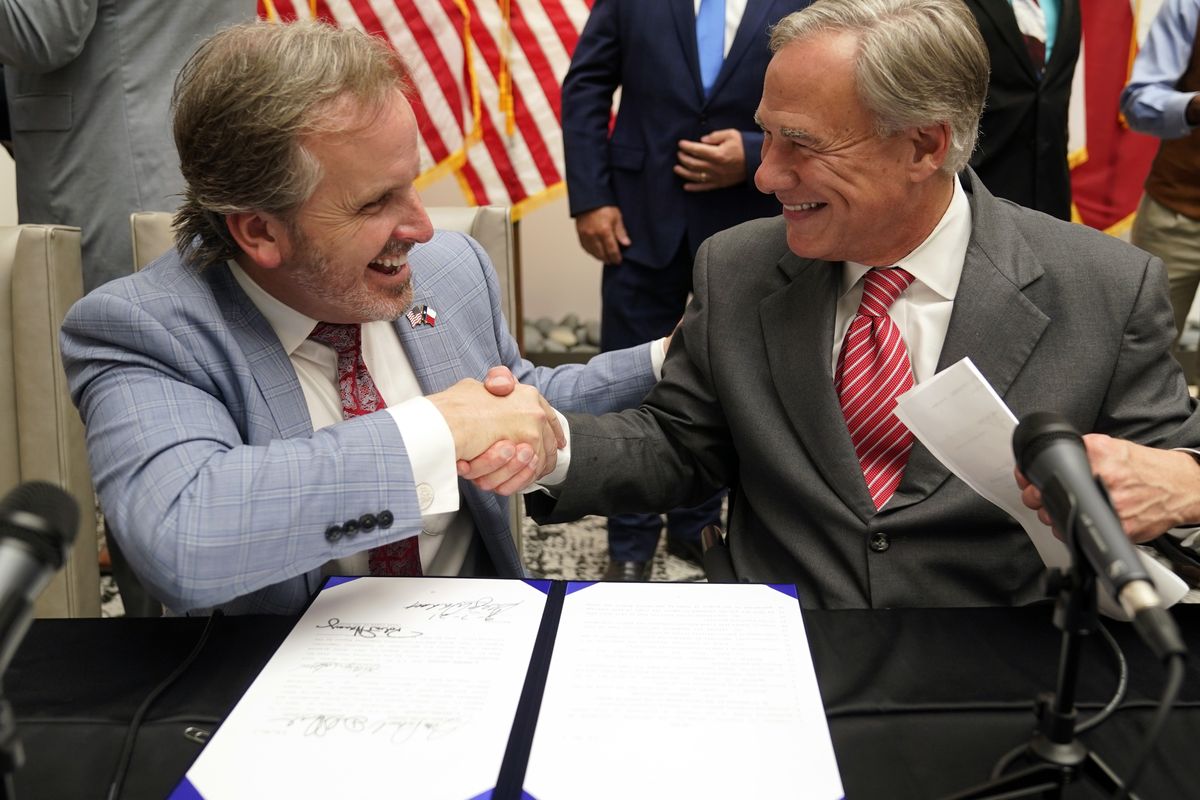 Texas Gov Greg Abbott and State Sen. Bryan Hughes, R-Mineola, shake hands after Abbott signed Senate Bill 1, also known as the election integrity bill, into law in Tyler, Texas, Tuesday, Sept. 7, 2021. The sweeping bill signed Tuesday by the two-term Republican governor further tightens Texas’ strict voting laws.  (LM Otero)
