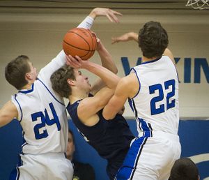 As Lake City's Jake Vetsch takes a shot, Coeur d'Alene's Ryan Walde (24) and Michael Hicks (22) defend in the first half during the rival Fight for the Fish game at CdA High School, Friday, Jan. 17, 2014. (Colin Mulvany / The Spokesman-Review)
