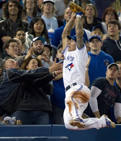 Toronto Blue Jays third baseman Brett Lawrie leaps into the crowd to catch a foul pop fly by Seattle Mariners' Munenori Kawasaki during the ninth inning of a baseball game in Toronto on Sunday, April 29, 2012. (Frank Gunn / The Canadian Press)