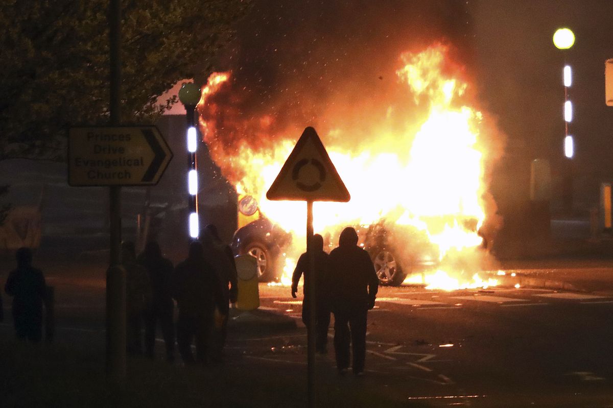 Masked loyalists are seen after hijacking and setting a car on fire at the Cloughfern roundabout in Newtownabbey, Belfast, Northern Ireland, Saturday, April 3, 2021. Masked men threw petrol bombs and hijacked cars in the Loyalist area North of Belfast. Loyalists and unionists are angry about post-Brexit trading arrangements which they claim have created barriers between Northern Ireland and the rest of the UK.  (Peter Morrison)