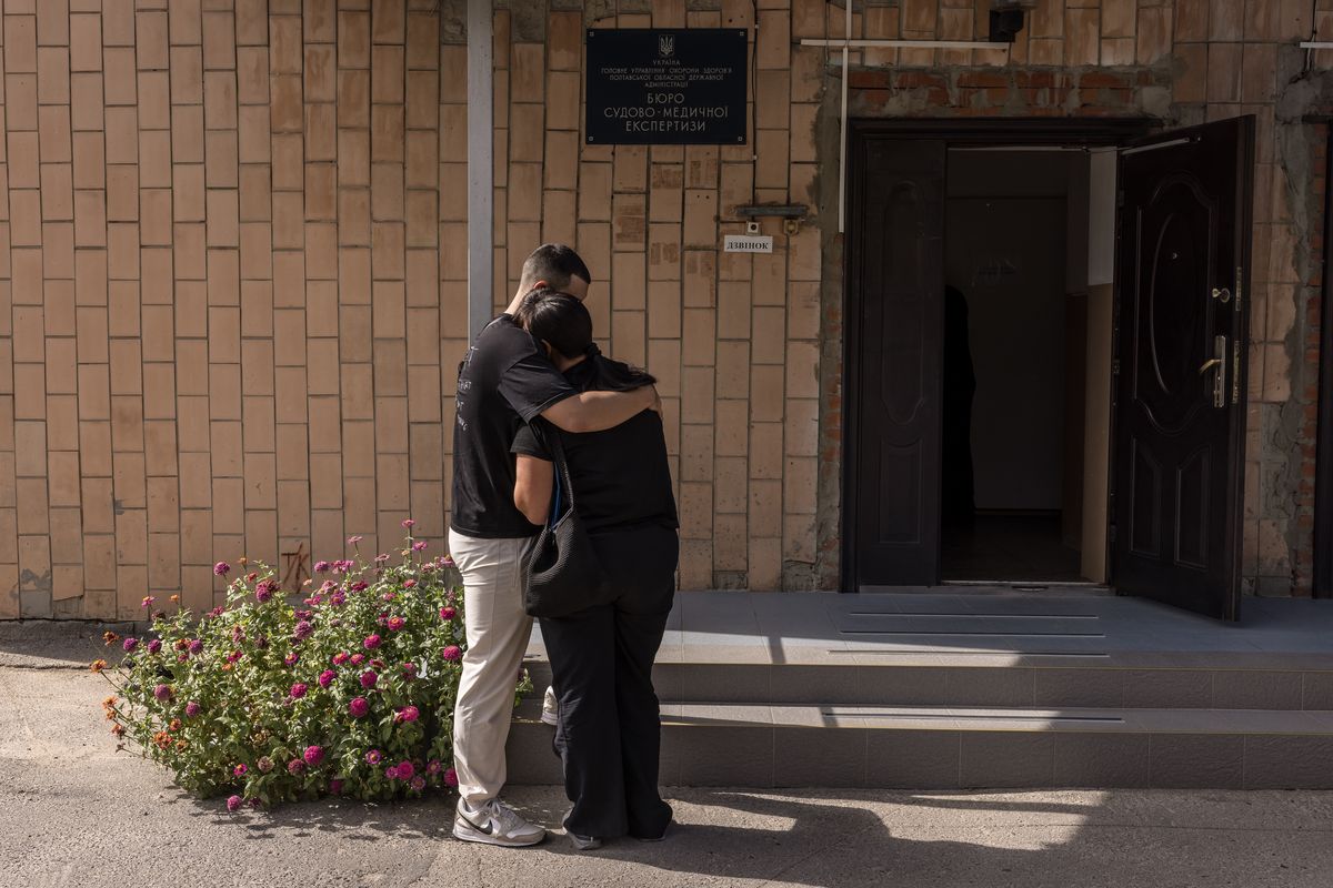 A man comforts a grieving woman Thursday after she received a relative