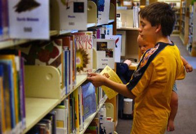 
Jacob Storebo, 13, cruises the stacks with his 10-month-old brother, Cody, at the Otis Orchards Library on Thursday. 
 (Liz-Anne Kishimoto / The Spokesman-Review)