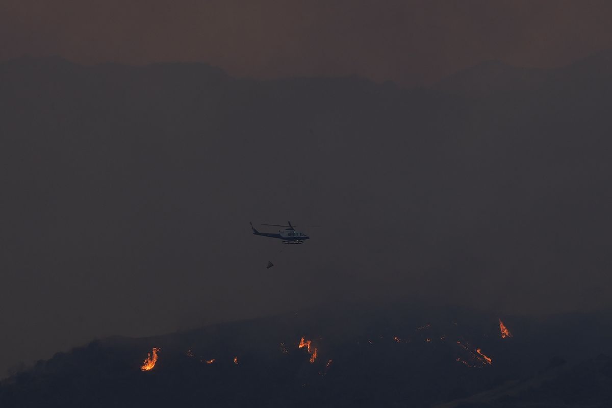 A helicopter flies overa forest fire, in the Larnaca mountain region, Saturday, July 3, 2021. Cyprus has asked fellow European Union nations to help battle a huge forest fire in a mountainous region of the east Mediterranean island nation that has forced the evacuation of at least three villages. Cypriot Environment Minister Costas Kadis told state broadcaster Saturdasy that the fire has claimed “huge tracts of forest” and private property near the village of Arakapas in the Troodos mountain range.  (Petros Karadjias)