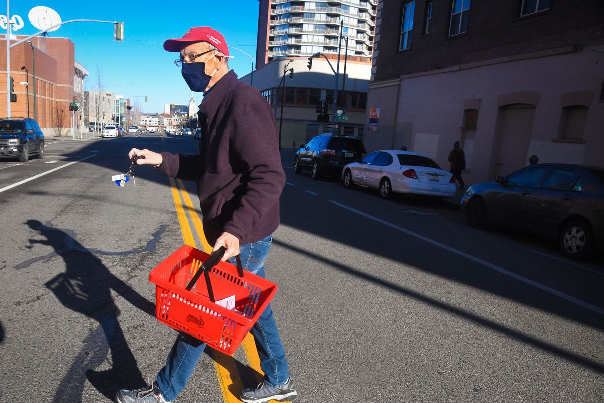 Jon Louis, 83, walks across Adams Street while delivering Meals on Wheels at the Parsons, Tuesday, Dec.1, 2020 in downtown Spokane.  (DAN PELLE/THE SPOKESMAN-REVIEW)