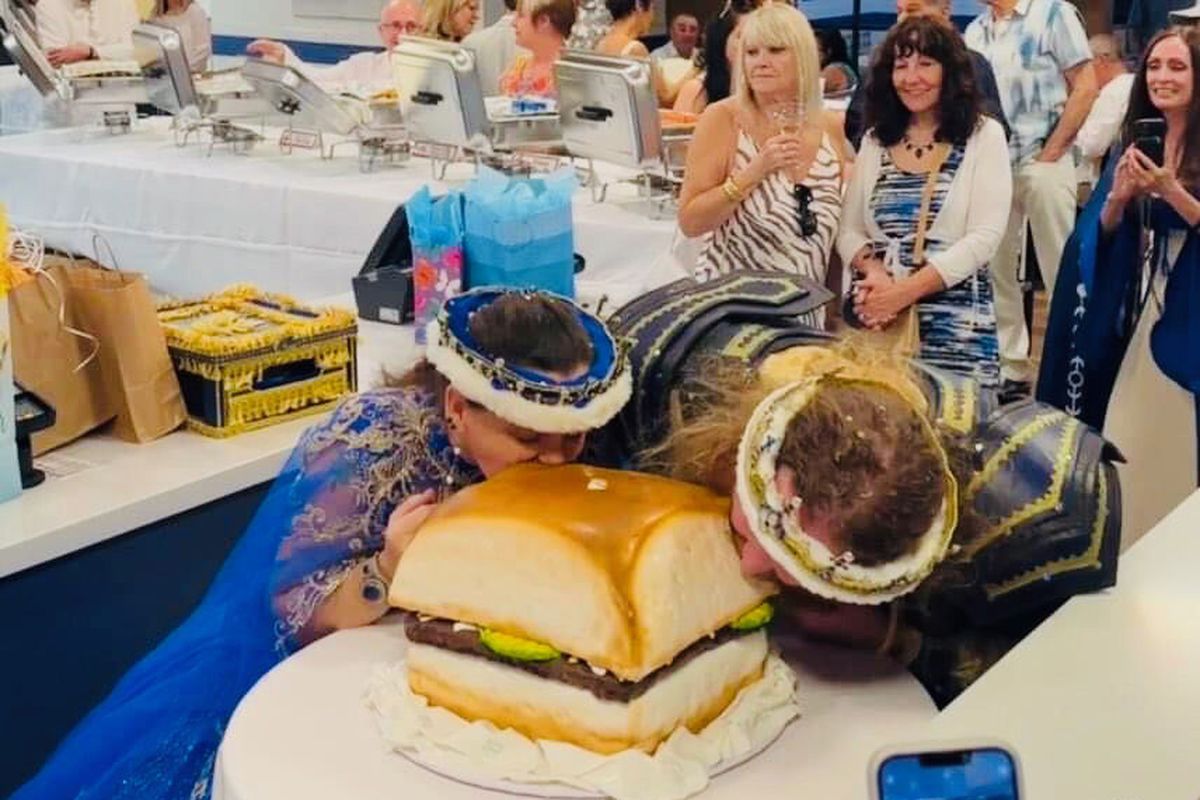 Jamie West and Drew Schmitt bite into their wedding cake, shaped like a White Castle slider. They were married at a White Castle in Scottsdale, Ariz., on May 5, 2023.    (Orlando Brown)