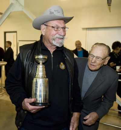 FILE - In this Oct. 11, 2012, file photo from Toronto , former Toronto Maple Leafs player Johnny Bower, right, looks at Eddie Shack's personalized miniature Stanley Cup from the 1962 championship. Shack, one of the NHL’s most colorful players on and off the ice, has died. He was 83. The Maple Leafs announced the news in a tweet Sunday, July 26, 2020.  (Aaron Vincent Elkaim)