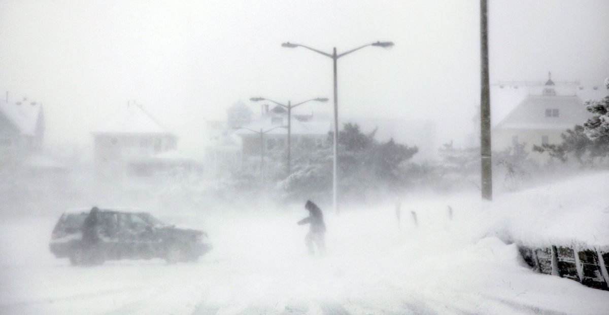 A few people brave the wind coming off the bay during a snowstorm  in Norfolk, Va., on Sunday.  (Associated Press)