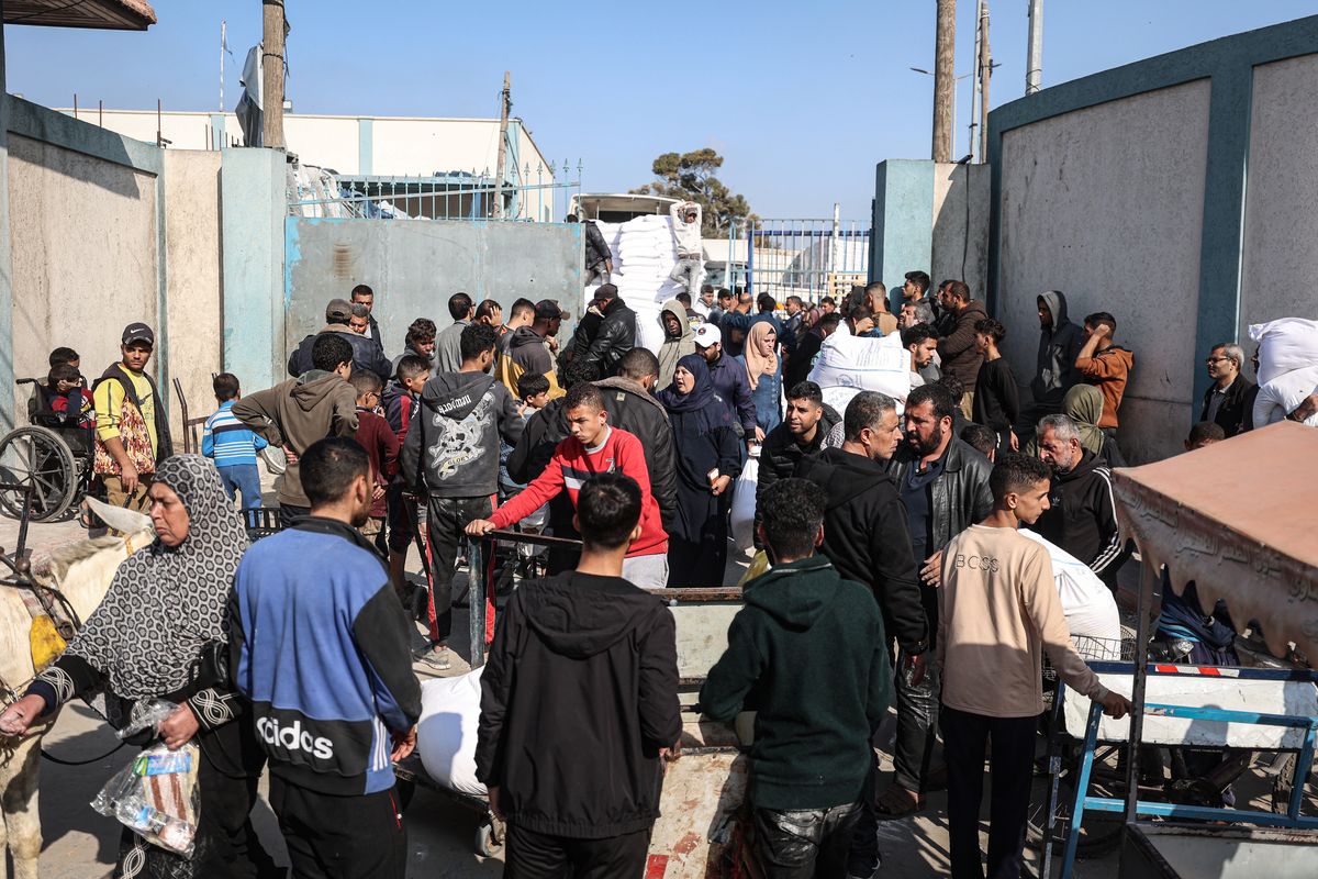 Palestinians wait to receive bags of flour on Jan. 1 outside U.N. warehouses east of Rafah in the southern Gaza Strip.  (Loay Ayyoub/for The Washington Post)