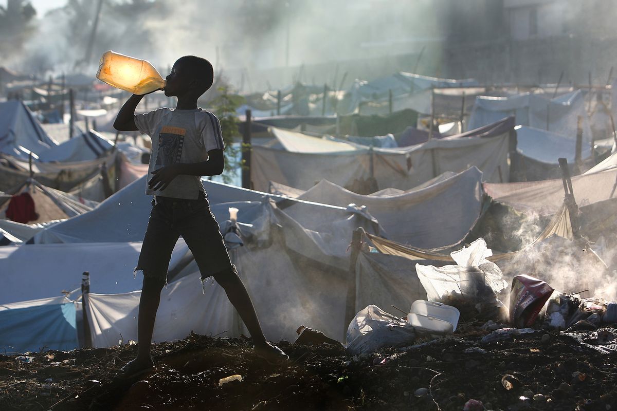 Rudeson Laurent, 10, takes a drink of water after brushing his teeth near a burning pile of trash inside the Daihatsu tent camp on the outskirts of Port-au-Prince, Haiti, last week. Los Angeles Times (Los Angeles Times)