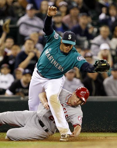 Seattle Mariners third baseman Alex Liddi, left, and Los Angeles Angels' Peter Bourjos collide at third base after a throwing error by pitcher Brandon League went past Liddi in the ninth inning in a baseball game Friday, May 25, 2012, in Seattle. The Angels won with three runs in the ninth inning, 6-4. (Elaine Thompson / Associated Press)