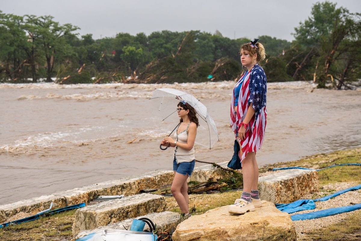 Laeighton Sterling, right, and Nicole Whelam observe flood waters from the banks of the Guadalupe River on Friday in Kerrville, Texas. Heavy rainfall caused flooding along the Guadalupe River in central Texas with multiple fatalities reported.  (Getty Images)