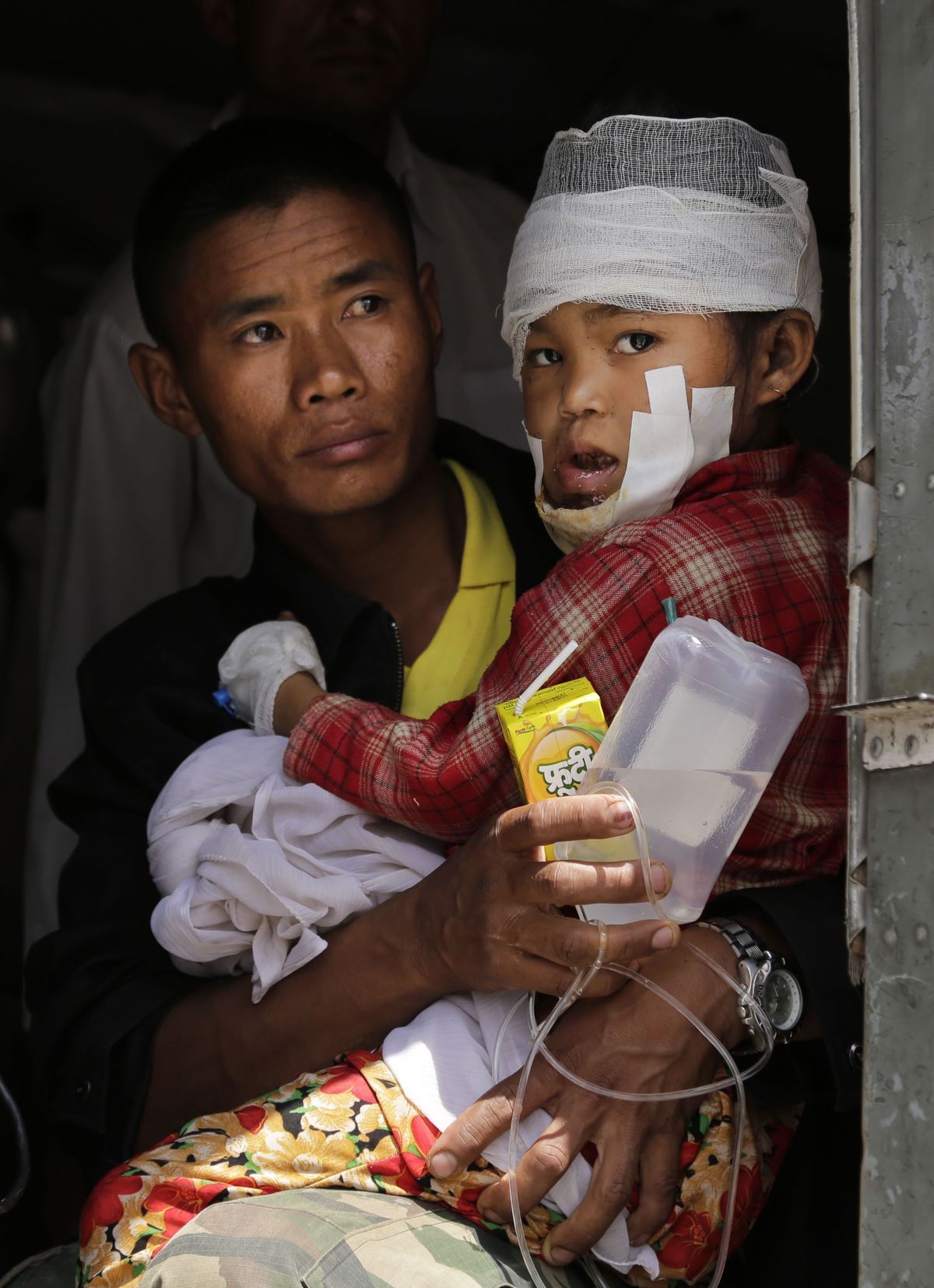 An injured child is carried by a Nepalese soldier as they wait to leave an Indian Air Force helicopter in Kathmandu, Nepal, Monday. (Associated Press)