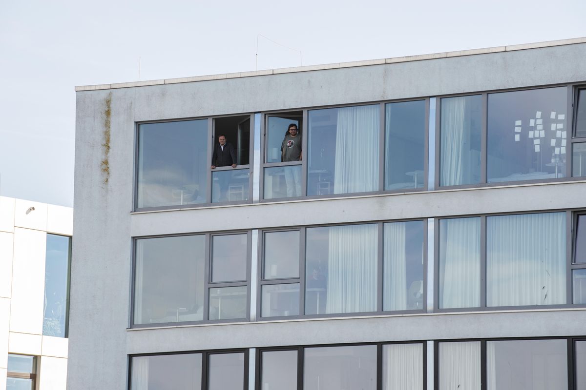 In this photo provided by the Alfred-Wegener-Institut,  taken  May 6, MOSAiC participants stand at the window of their rooms in the hotel where they are  quarantined. (Esther Horvath / Associated Press)