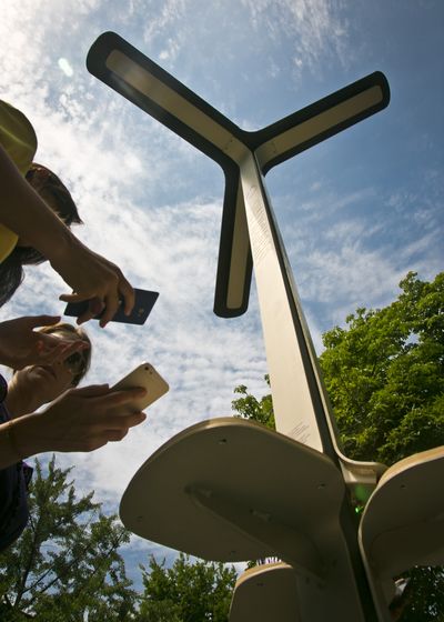 Users check their phones after solar charging the devices Tuesday in New York. The city plans to install 25 stations over the summer. (Associated Press)