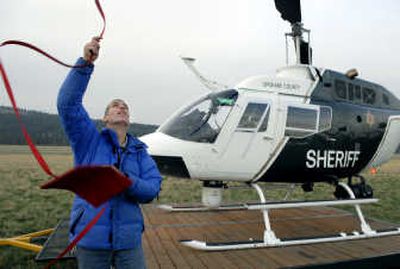 
Pilot Dave Valenti tosses a tie-down line over the Spokane County Sheriff's Office chopper's rotor blade after landing Wednesday at Felts Field in Spokane.
 (Dan Pelle / The Spokesman-Review)