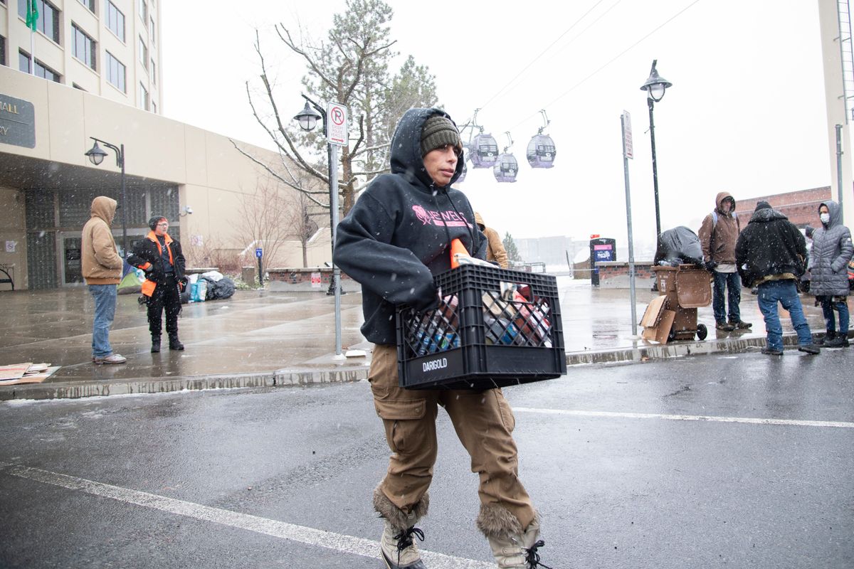 Julie Garcia, of the group Jewels Helping Hands, hauls food and personal items from a tent camp to a vehicle Thursday outside Spokane City Hall where people had been camping and protesting.  (Jesse Tinsley/The Spokesman-Review)