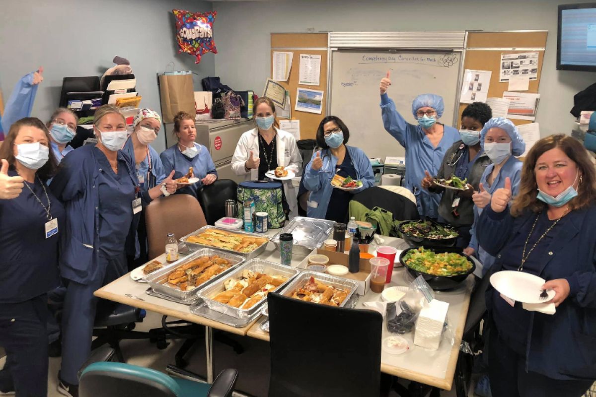 In this March 26, 2020, photo provided by Maureen Morin and Federico’s Pizza, staff members of the Hackensack Meridian Jersey Shore University Medical Center give a thumbs-up in Neptune City, N.J., as they eat a donated meal from the Belmar, New Jersey pizzeria. (Maureen Morin / Associated Press)