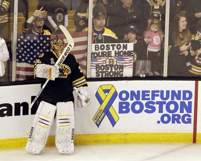 Fans held patriotic signs as goalie Anton Khudob and the Bruins played the first hockey game in Boston since the manhunt. (Associated Press)