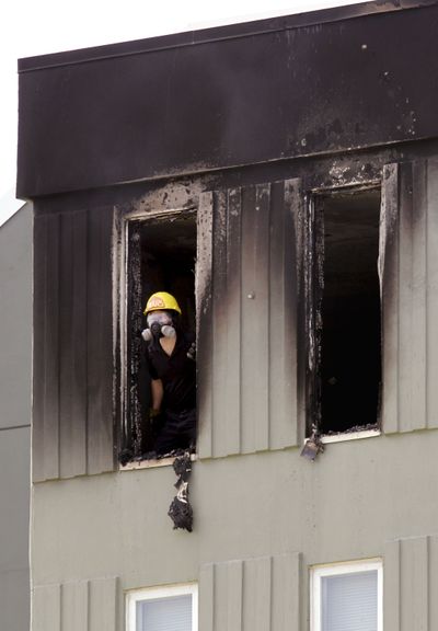 Burned out. A fire investigator peers out of a charred top-floor apartment where a fire broke out Thursday in Seattle. Firefighters quickly doused the 11th-floor fire, in the same building as a fatal fire in 2010, adjacent to Interstate 5. The building doesn’t have a sprinkler system because it was built before city codes required them. (Associated Press)