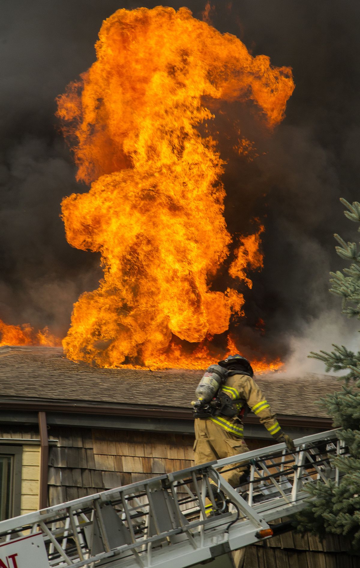 Facing a geyser of flames, a Spokane firefighter heads to an apartment building’s roof on South Lincoln Street on Tuesday. (Colin Mulvany)
