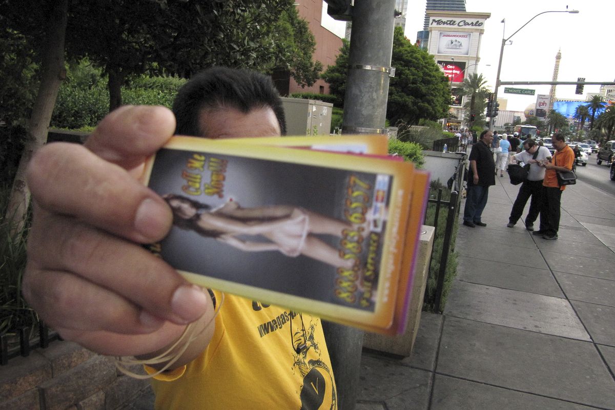 An unidentified man on a Las Vegas Strip sidewalk hands out cards advertising exotic dancers on Wednesday, Aug. 29, 2012. Las Vegas officials have passed a litter ordinance requiring such �handbillers� to pick up after tourists who drop the materials. The American Civil Liberties Union says the new ordinance might violate free speech protections. (Mead Gruver / Associated Press)