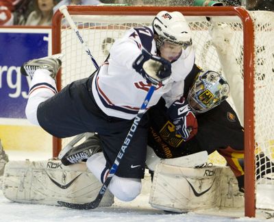 Team USA’s Drayson Bowman smashes German goalie.  (Associated Press / The Spokesman-Review)