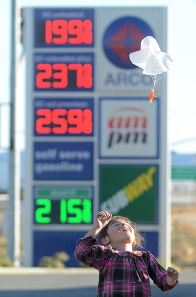 In this  Feb. 24 file photo, Joanna Alvarez plays with a toy parachute man at an Arco gas station parking lot in Oak Hills, Calif. Gasoline prices are expected to keep rising until summer but remain far cheaper than recent years, due to the worldwide glut of oil. (David Pardo / Associated Press)