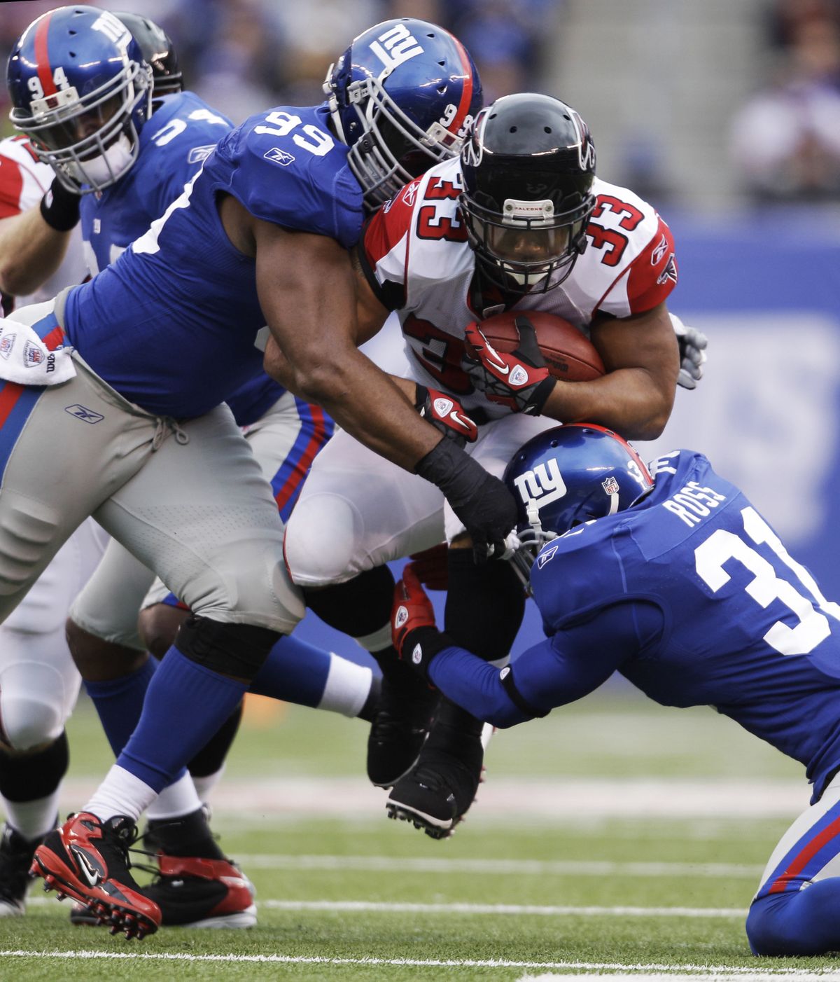 Giants’ Chris Canty, left, and Aaron Ross bottled up Falcons RB Michael Turner. (Associated Press)