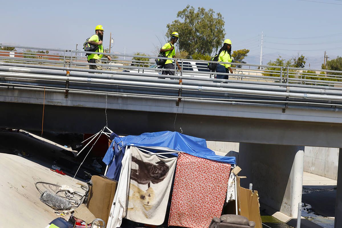 Richard Lopez, left, a HELP of Southern Nevada Homeless Response Team lead, Rayvonte Toliver, center, and Zabrena Quinn, both HELP of Southern Nevada outreach workers, check out homeless encampment at Mountain Vista Street and Russel Road wash, on Tuesday in Las Vegas. HELP of Southern Nevada travels the streets with flyers about heat, water and vehicles to transport people to cooling centers.  (Bizuayehu Tesfaye/Las Vegas Review-Journal/TNS)