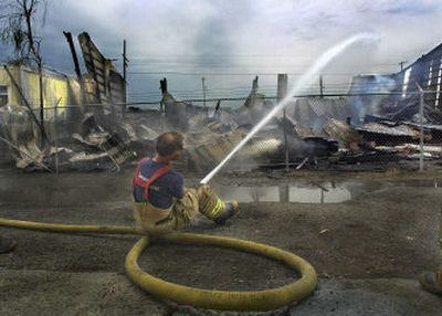 
Spokane firefighter Ken Miller hoses the smoldering ruins of a roofing business at Sprague and Cowley on Friday. The late night fire destroyed the building. 
 (Christopher Anderson/ / The Spokesman-Review)