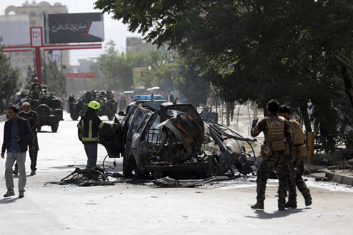 Afghan security personnel inspect the site of a bomb explosion in Kabul, Afghanistan, Saturday, June 12, 2021. Separate bombs hit two minivans in a mostly Shiite neighborhood in the Afghan capital Saturday, killing several people and wounding others, the Interior Ministry said.  (Rahmat Gul)