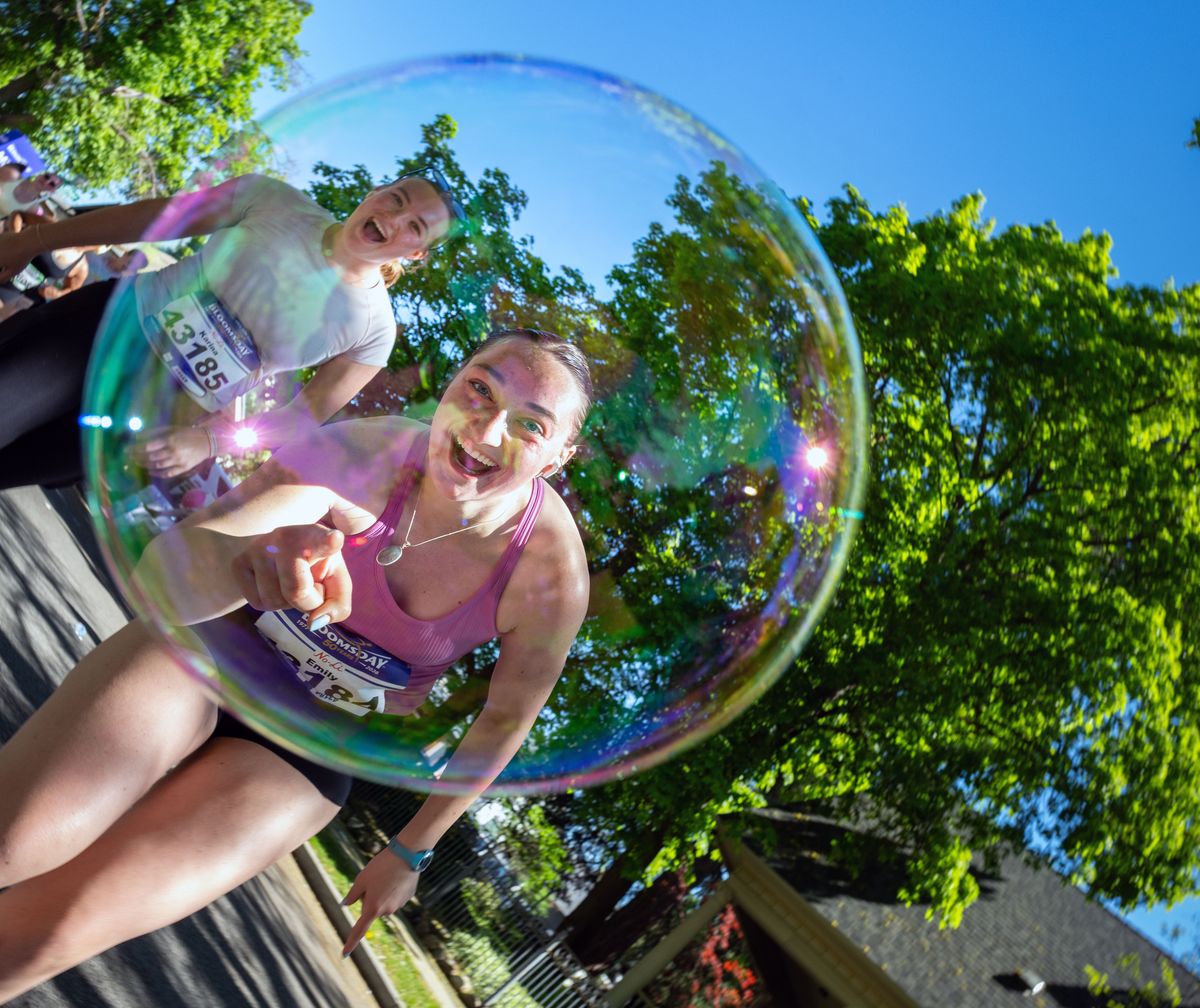 Emily Nelson pops a large bubble as she runs along Lindeke Street during the 50th annual Lilac Bloomsday Run on Sunday in Spokane.  (COLIN MULVANY /THE SPOKESMAN-REVIEW)