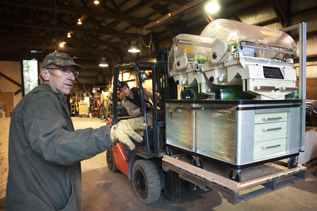 Gary Bartholomew, left, helps guide his son Rod’s fork lift into position Friday when loading a pair of hospital incubators into a 40-foot-long container on  West Lincoln Road near Four Mound Road. (Dan Pelle / The Spokesman-Review)