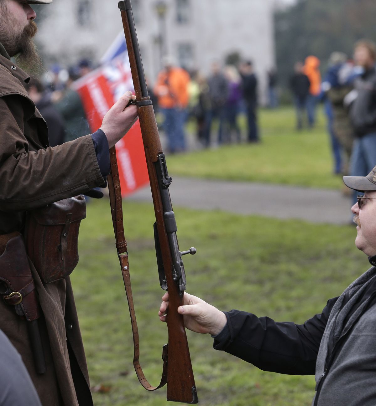 Demonstrators hand off a gun between them during a rally by gun-rights advocates to protest a new expanded gun background check law in Washington on Saturday in Olympia. (Associated Press)