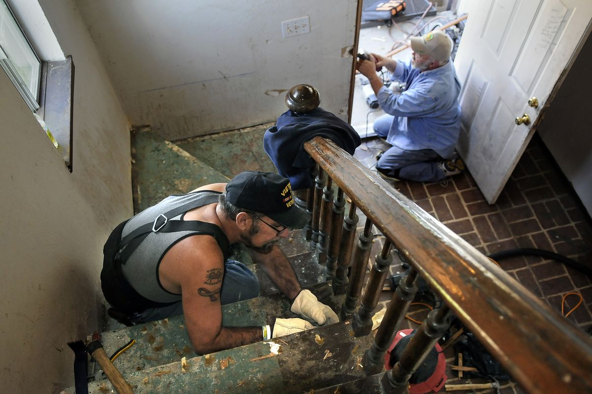 Volunteer Dave Brizius, left, pulls carpet staples while Stan Campbell of Project HOPE rebuilds the front door jamb Saturday at Tim Boit and Kathryn Lewis’ apartment  in Spokane’s West Central neighborhood.  (Dan Pelle)