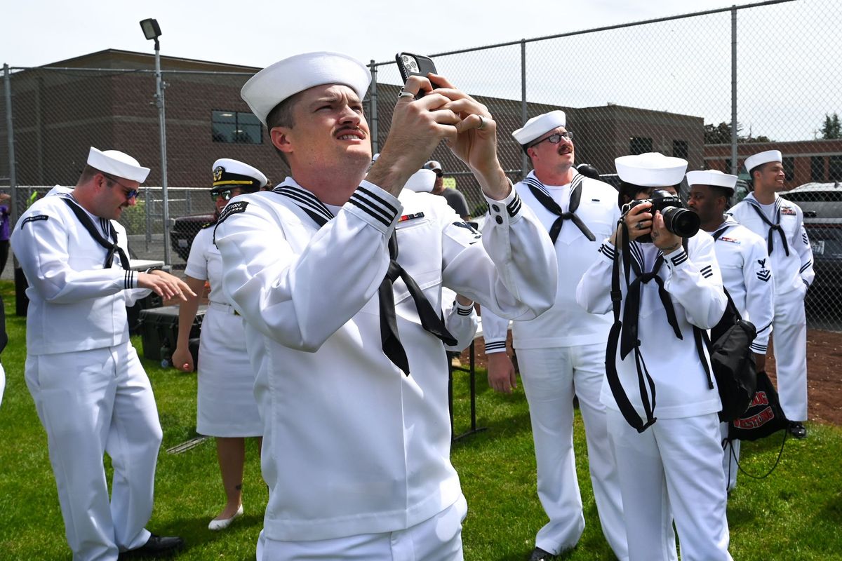 Navy members await the Leap Frogs parachute team to touch down on the grounds of St. Aloysius Catholic School, Wednesday, May 15, 2024, in Spokane. Members are in Spokane as part of Navy Week.  (DAN PELLE/THE SPOKESMAN-REVIEW)