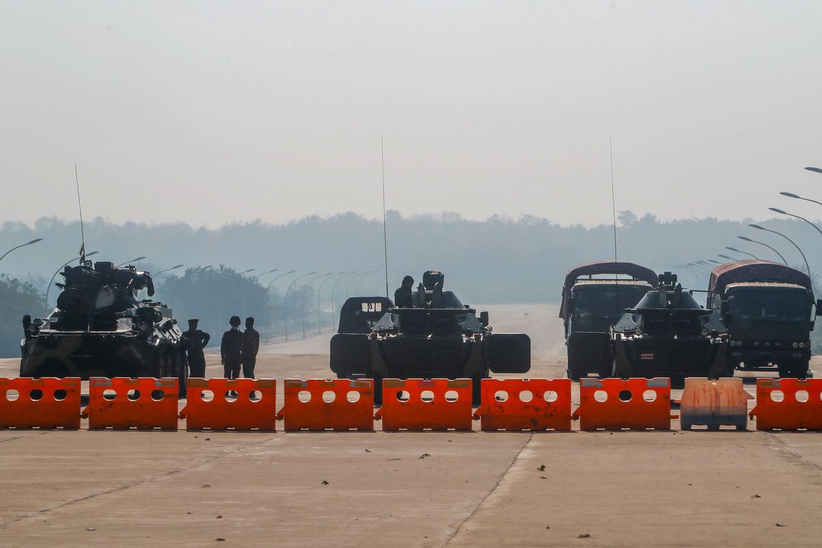 Myanmar’s military stand guard at a checkpoint manned with an armored vehicles blocking a road leading to the parliament building Tuesday in Naypyitaw, Myanmar.  (STR)