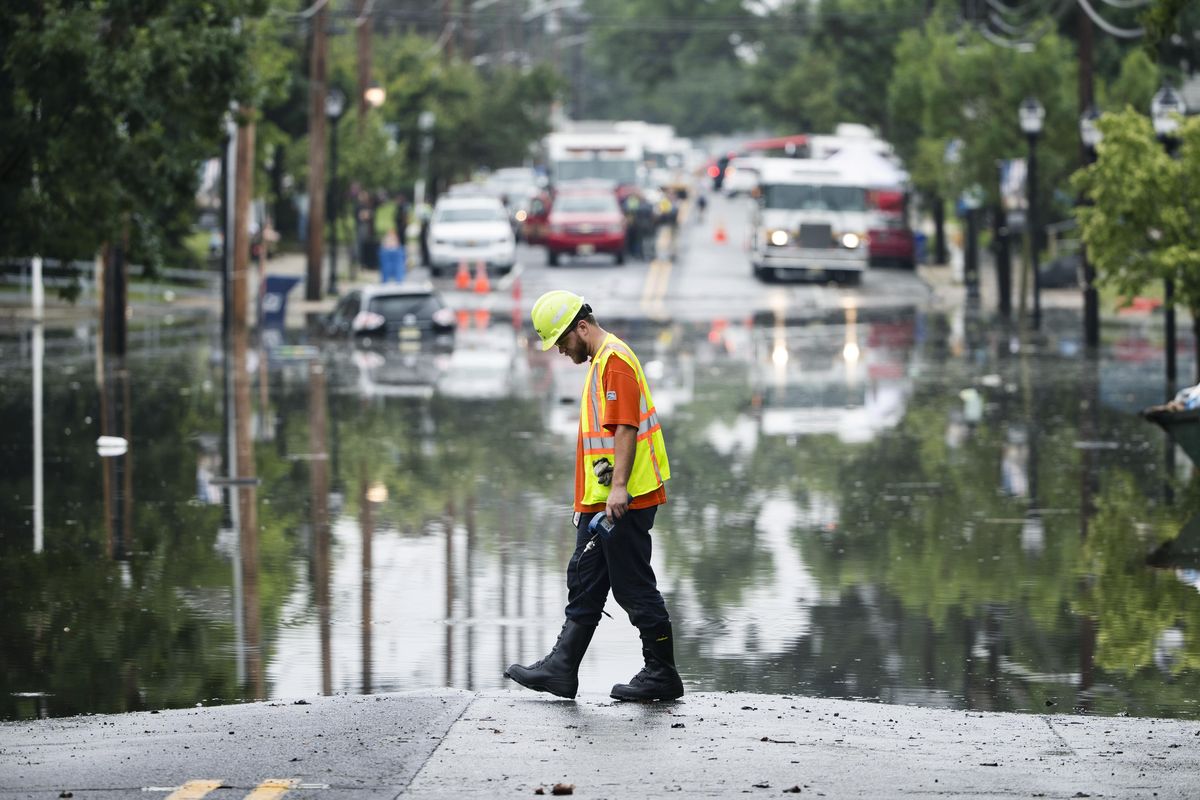 A utility worker walks the edge of the floodwaters submerging Broadway in Westville, N.J. Thursday, June 20, 2019. (Matt Rourke / associated press)