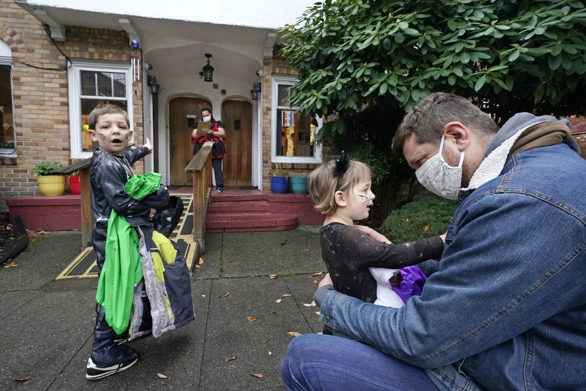 Alex Stonehill gets a goodbye from his daughter Helenore, 2, as her brother Malcolm, 4, motions to a friend arriving at the Community Day Center for Children on Oct. 29 in Seattle.  (Elaine Thompson)
