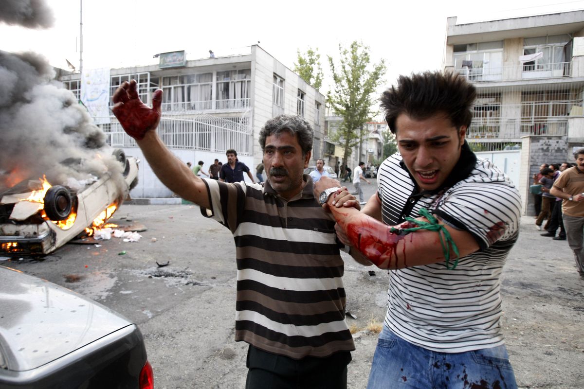 A protester allegedly injured by gunfire from pro-government militia is helped by another protester near a rally for opposition presidential candidate Mir-Hossein Mousavi on Monday in Tehran, Iran.  (Associated Press / The Spokesman-Review)