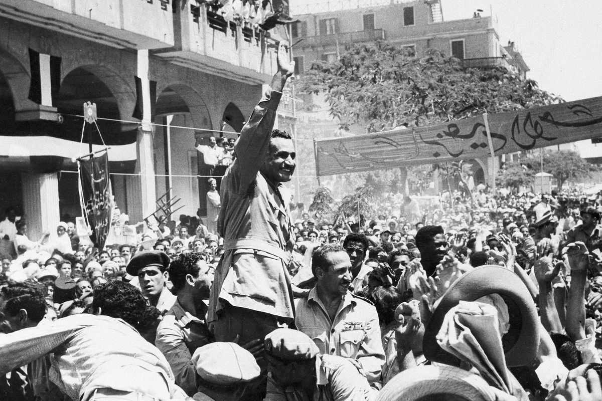 FILE - In this June 18, 1956 file photo, Egyptian leader Gamal Abdel Nasser waves as he moves through Port Said, Egypt, during a ceremony in which Egypt formally took over control of the Suez Canal from Britain. Since it opened in 1869, the canal has been a source of national pride and a focus of international conflict. Now, a skyscraper-sized container ship called the Ever Given got stuck sideways across the waterway since Tuesday, March 23, 2021 . The obstruction has halted canal traffic, valued at over $9 billion a day.  (STR)
