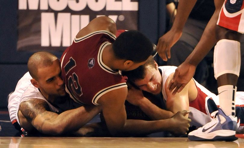 Gonzaga's Kevin Pangos, right, holds on to the ball as he fights with Loyola Marymount's LaRon Armstead, center, and teammate Robert Sacre, left, until the ref blows the whistle for a held ball Saturday, Feb. 11, 2012 at McCarthey Athletic Center. (Jesse Tinsley / The Spokesman-Review)