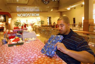 
Former Spokane Shock defensive lineman Devon Parks wraps a gift outside Nordstrom on Tuesday at River Park Square, where he operates a gift wrapping kiosk that helps the Wishing Star Foundation. He says that volunteering several years ago as a wrapper for a charity taught him how to wrap gifts properly. 
 (Jesse Tinsley / The Spokesman-Review)