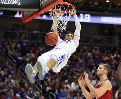 Kentucky's Jamal Murray, left, hangs from the rim after dunking over Indiana's Max Bielfeldt, right, during a second-round men's college basketball game in the NCAA Tournament. (Nati Harnik / Associated Press)